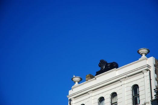white building in cardiff with black sculpture of Lion on the roof against very blue sky without clouds in sunny summer day