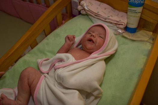 One month old caucasian girl swaddled in white blanket after a bath.