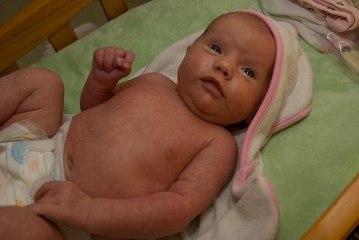 One month old caucasian girl swaddled in white blanket after a bath.