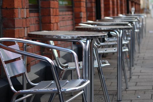 tables and chairs on the street in front of a restaurant