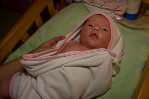 One month old caucasian girl swaddled in white blanket after a bath.