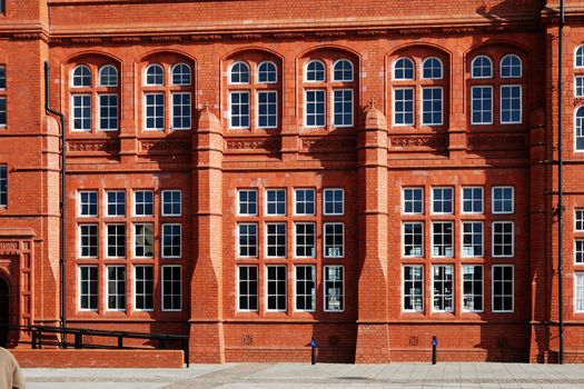 wall of red historical building in cardiff bay with windows