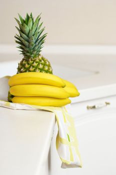 Bananas and ananas on white kitchen's table