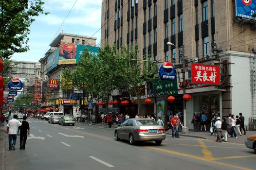 CHINA, SHANGHAI, NANJING ROAD - May 13, 2007: famous Nanjing Road, shopping paradise, thousands of shops and restaurants, crowd of people, taxis, bikes and scooters. Most busy street in Shanghai.