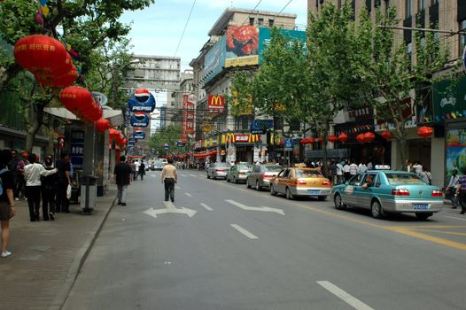 CHINA, SHANGHAI, NANJING ROAD - May 13, 2007: famous Nanjing Road, shopping paradise, thousands of shops and restaurants, crowd of people, taxis, bikes and scooters. Most busy street in Shanghai.