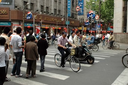 CHINA, SHANGHAI, NANJING ROAD - May 13, 2007: famous Nanjing Road, shopping paradise, thousands of shops and restaurants, crowd of people, taxis, bikes and scooters. Most busy street in Shanghai.