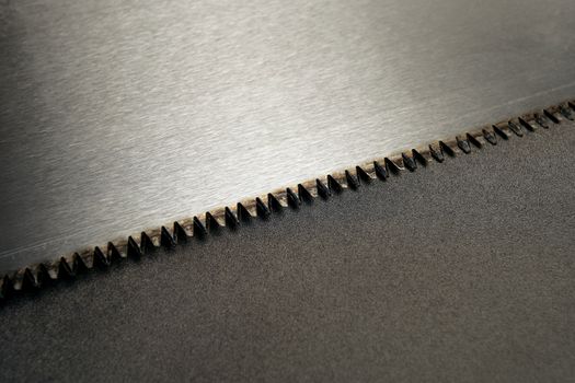 Closeup of a handsaw and its teeth.