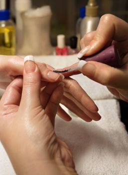 A manicurist applying nail polish during a manicure.
