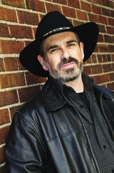 Man with beard in cowboy hat and leather jacket