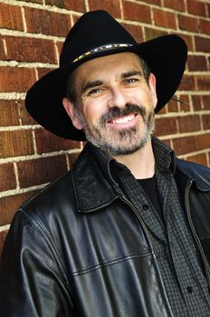 Man with beard in cowboy hat and leather jacket