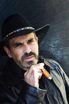 Man with beard in cowboy hat smoking cigar