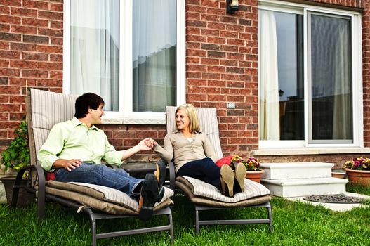 Happy couple in backyard of new home sitting on lounge chairs