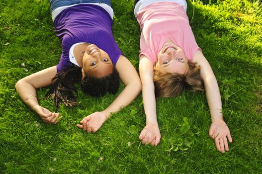 Two teenage girls laying on grass arms outstretched