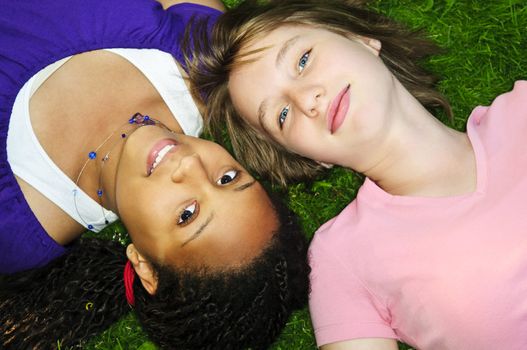Two teenage girls laying on grass looking up