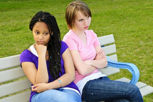 Two bored teenage girls sitting on bench