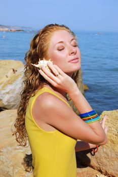 beautiful girl holds a seashell near ear