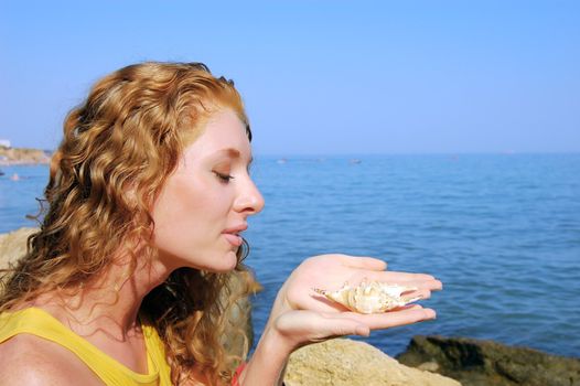 beautiful girl holds a seashell in hands