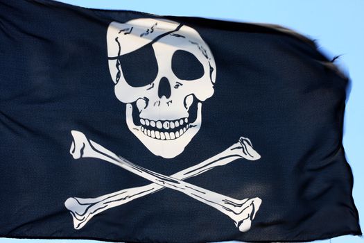 black pirate flag fluttering in the wind, parts of it blurry due to strong wind