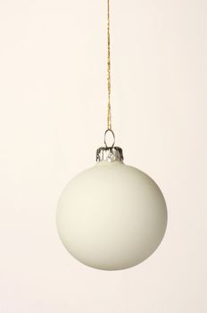 White christmas orb shot on white, hanging on a gold thread