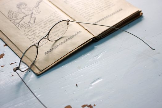 old fashioned reading glasses on top of an old book on a table 