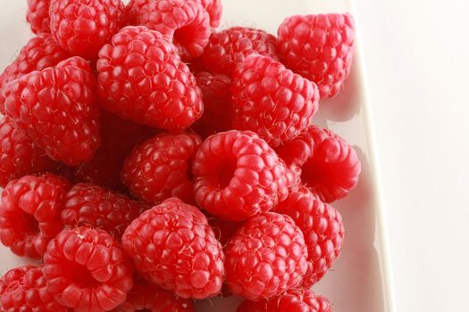 Bowl of fresh red raspberries isolated on white
