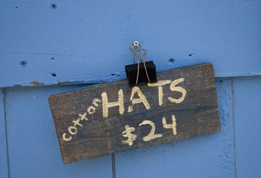 A hand lettered sign on an old board with a blue wood background.