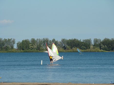 Backlit wind surfer on calm coastal water