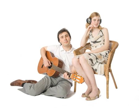 A woman in headphones and a man playing guitar for her
