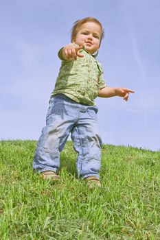 A child pointing at camera, against blue sky