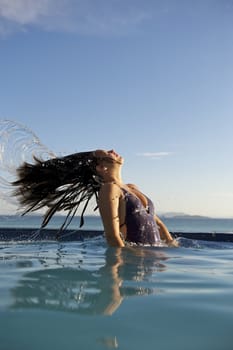 Woman relaxing on a swimming pool with a sea view in Rio de Janeiro, Brazil