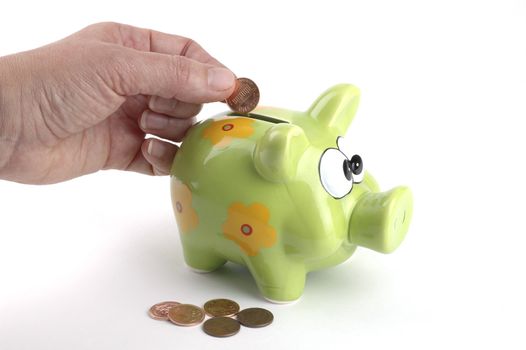 Female hand putting a penny in a coin bank.