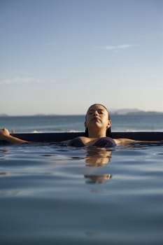 Woman relaxing on a swimming pool with a sea view in Rio de Janeiro, Brazil