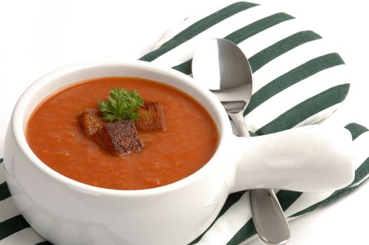 Bowl of garden tomato soup with croutons and parsley.