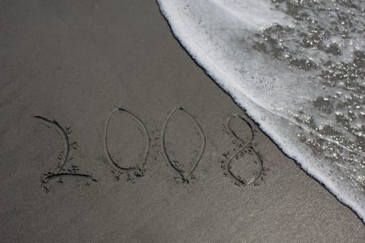 Water on a beach about to wipeout 2008 written in sand