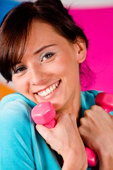 Beautiful young woman curls dumbbells with a happy smile