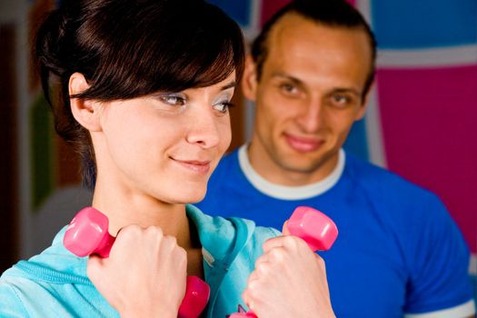 Smiling young woman at the health club with her personal trainer