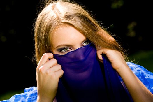 Lovely young woman dancing belly dance in blue outdoors
