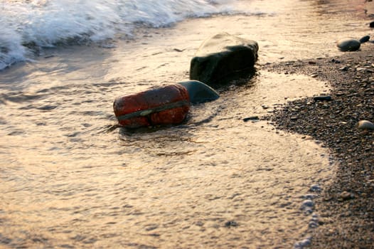 stones at sea shore covered with film of flowing water at sunset