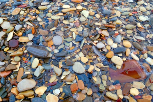 closeup of sea shore with pebbles covered with film of water