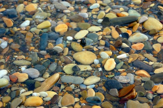 closeup of sea shore with pebbles covered with film of water