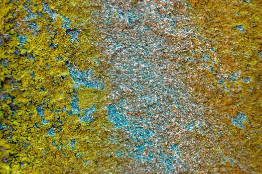 colored (prevaling yellow and blue) rough stone surface with lichen