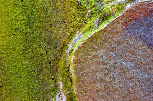 colored (prevaling green and brown) rough stone surface with lichen