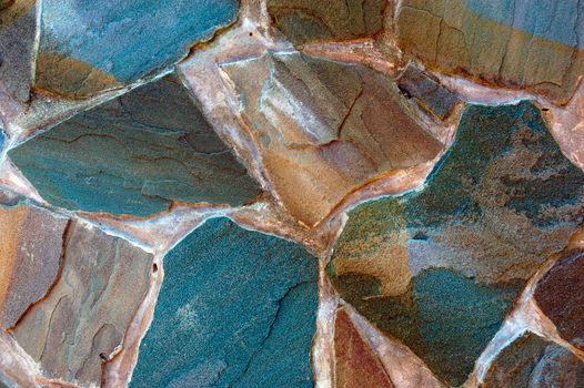 colored (prevaling blue and brown) rough wall surface made of wild stones