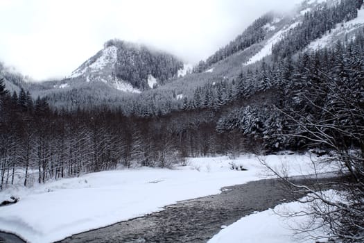 A stream flowing through snow covered mountains.