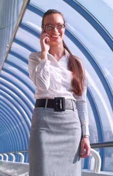 Beautiful young business woman in glasses speaks by phone