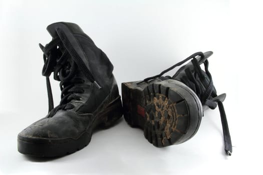 A pair of black, worn combat boots isolated on white.