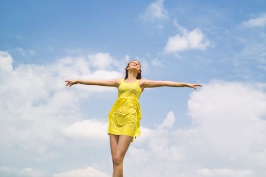 Beautiful lady in yellow dress smiling over sky