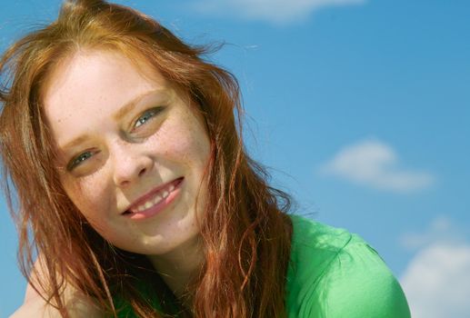 Beautiful lady in green smiling over sky