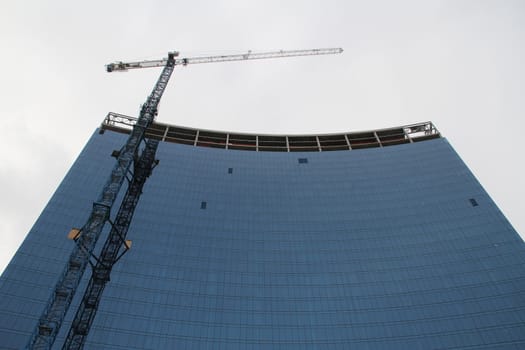 A glass building under construction with snow falling.