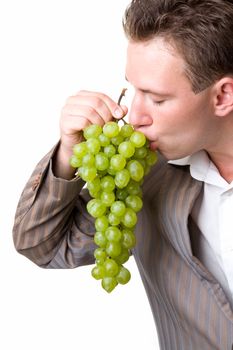 young man eats green grapes on a white background